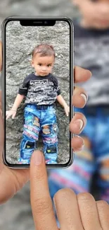 Hand holding phone with child's image as wallpaper.