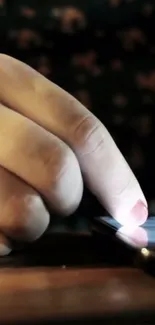 Close-up of a finger touching a smartphone screen, glowing in dim light.