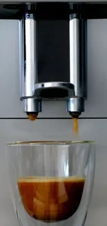 Close-up of a modern coffee machine brewing espresso into a clear glass cup.