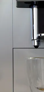 Sleek silver coffee machine with glass cup