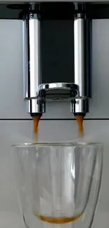 Stainless steel coffee maker pouring espresso into glass cups.