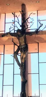 Modern crucifix sculpture in sunlit chapel with large windows.