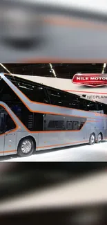 Sleek double-decker bus with gray and orange design at Nile Motors exhibition.