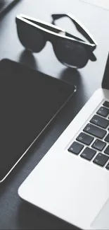 Modern workspace with laptop, tablet, and camera in grayscale setting.