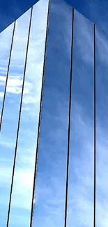 Tall glass building reflecting blue sky.