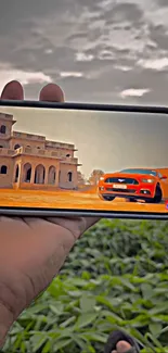 Smartphone displaying building and car image outdoors.