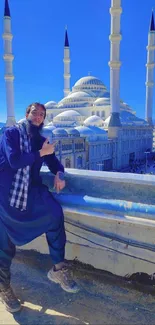 Man posing with mosque and blue sky background.