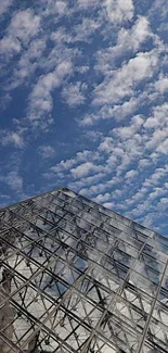 Glass building against a blue sky with clouds.