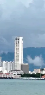 City skyline with a tall tower against a cloudy sky.