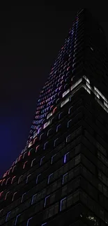 Tall skyscraper with LED lights at night in a cityscape view.