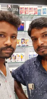 Two individuals in mobile store with colorful phone displays.