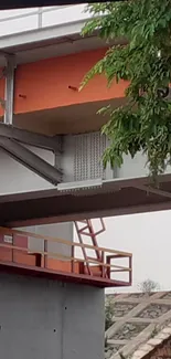 Modern urban bridge with orange and grey accents surrounded by greenery.