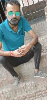 Man with sunglasses sitting against brick wall