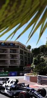 Formula 1 car racing on Monaco's street circuit under palm tree.