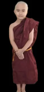 Young monk in maroon robe with a black background.