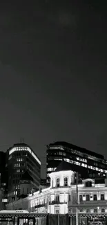 Black and white cityscape with illuminated architecture at night.