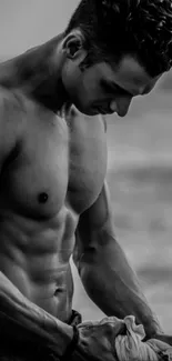 Monochrome image of a muscular man at the beach, embodying fitness and strength.