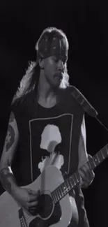 Black and white image of a guitarist with a bandana playing an acoustic guitar.