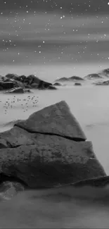 Monochrome mountain landscape with rocks and starry sky.