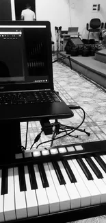 Monochrome music studio with keyboard and computer setup.