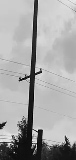 Black and white silhouette of a power line against a cloudy sky.