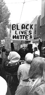 Protesters holding a Black Lives Matter sign in a monochrome street scene.