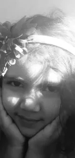 Monochrome portrait of a smiling child with a floral headband.