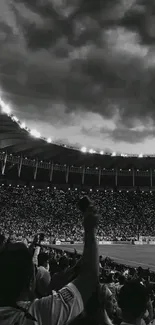 Monochrome stadium with a cloudy night sky and cheering crowd.