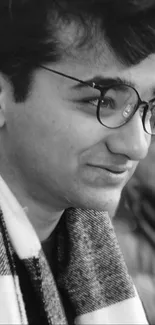 Monochrome portrait of a thoughtful young man in glasses and a scarf.