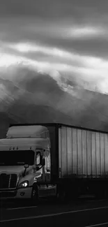 Monochrome image of a truck on a mountain road under cloudy skies.