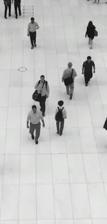 Monochrome image of people walking on a tiled urban walkway.