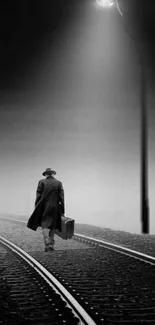 Monochrome wallpaper of a lone traveler under a streetlight on train tracks.