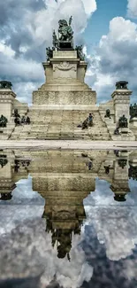 Monument reflected in calm water, under a dramatic cloudy sky.