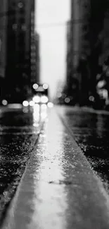 Black and white cityscape with rainy street and lights.