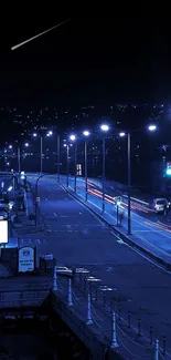 Dark blue city street at night with glowing lights.