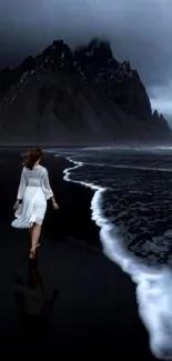 Moody mountain and beach with dark ocean waves at dusk.