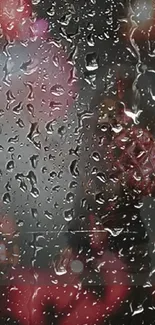 Moody raindrops on glass with a blurred pink and red background.