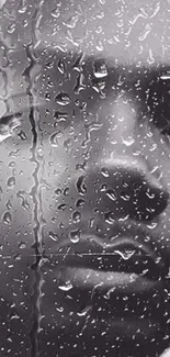 Close-up of raindrops on glass with a contemplative face in grayscale.