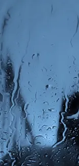 Raindrops on a window with a blue background, creating a moody mobile wallpaper.