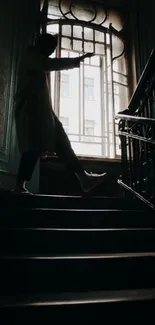 Silhouette of a person on a dimly lit staircase by a window.