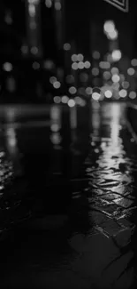 Moody black and white urban night street with city lights reflecting on wet pavement.