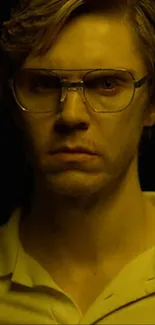 A portrait of a man with glasses in moody yellow lighting.