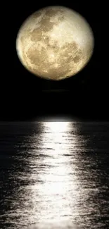 Luminous full moon reflecting over a calm ocean at night.