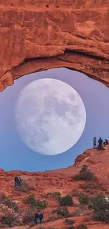 Moonlit desert arch with full moon in background.