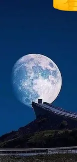 Moonlit mountain view with full moon and dark blue sky.