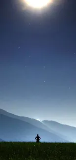 Silhouetted figure under a moonlit mountain sky wallpaper.