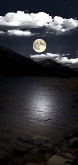 Moonlit lake with clouds and mountains at night.