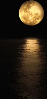 Golden full moon reflected on calm dark water at night.