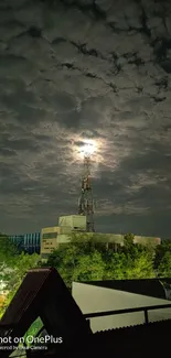 Moonlit tower and cloudy night sky with lush green surroundings.