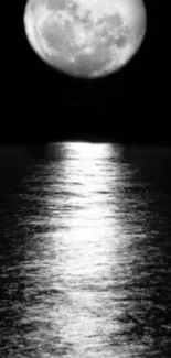 A full moon reflecting over a calm ocean at night, in black and white.